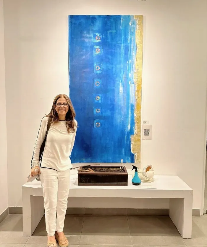 Elsa Basil de pie junto a En el inmenso mar, su pintura azul de gran altura, en una exposición
