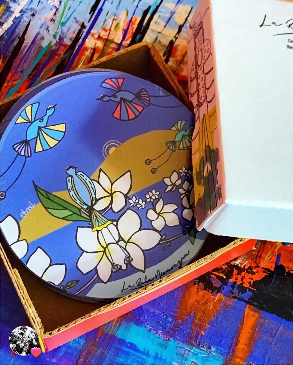 A blue gift box holding a plate illustrated with birds and white flowers
